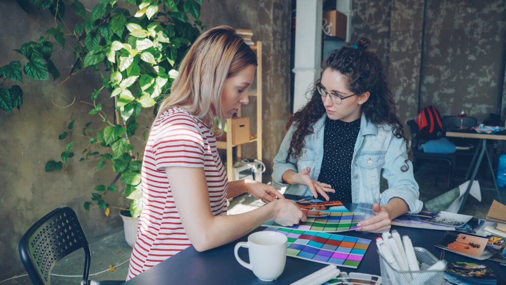 Two women discuss colors and designs together.