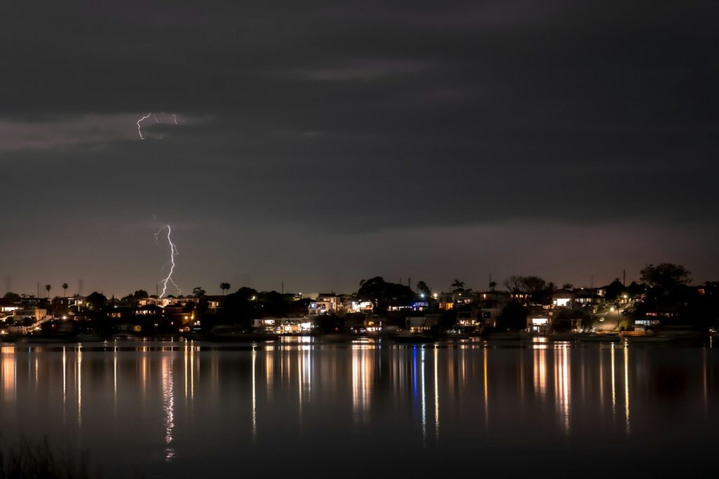 Lightning strikes over a city skyline at night.
